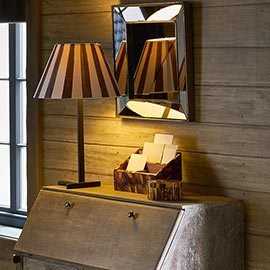 Stripy lampshade and mirror in a dark corner on a chest